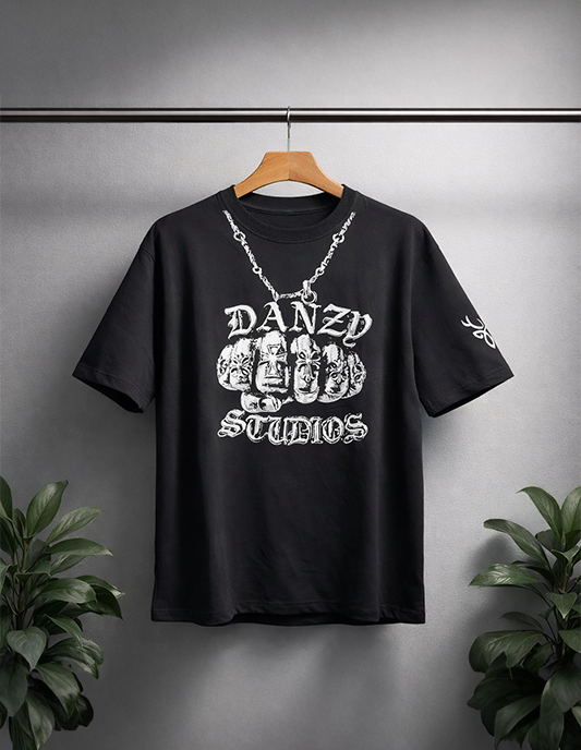 Black t-shirt with white graphic design and 'DANZY STUDIOS' text on a hanger against a gray background.