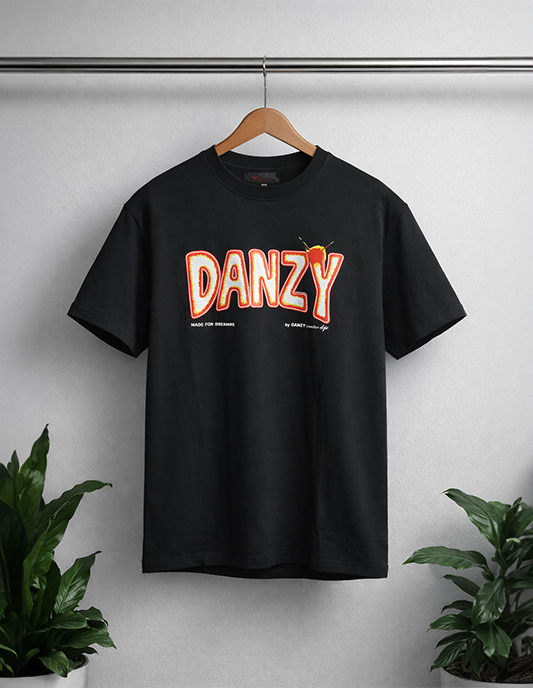 Black t-shirt with 'DANZY' text on a hanger against a white wall with plants.