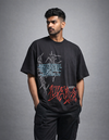 Man wearing a black t-shirt with graphic designs on a gray background