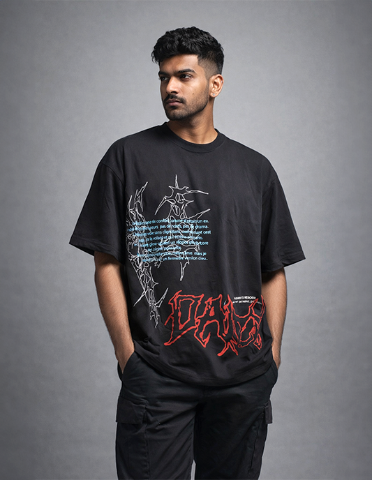 Man wearing a black t-shirt with graphic designs on a gray background
